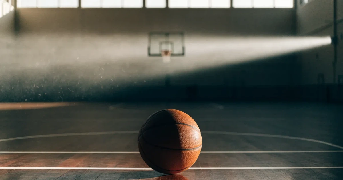 Un pallone da calcio sul dischetto del centrocampo di un prato, alla luce del mattino